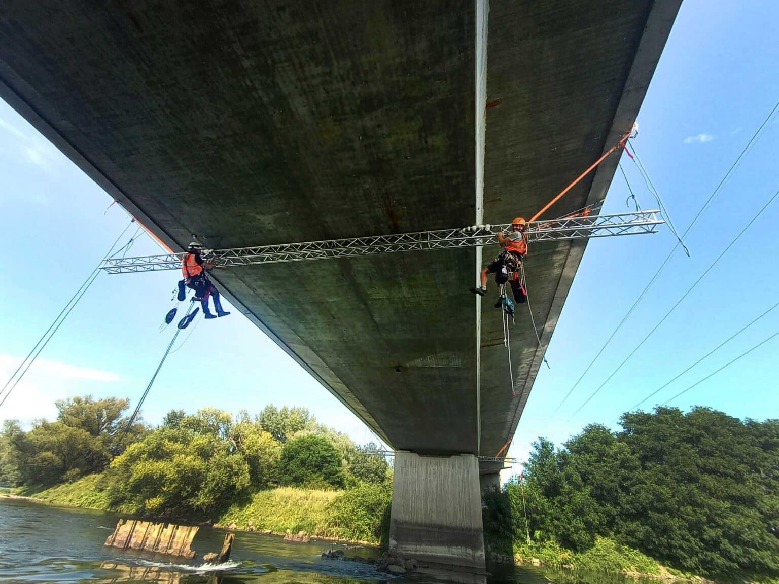 Zwei Monteuere bei der Montage von Sensortechnik unter einer Brücke